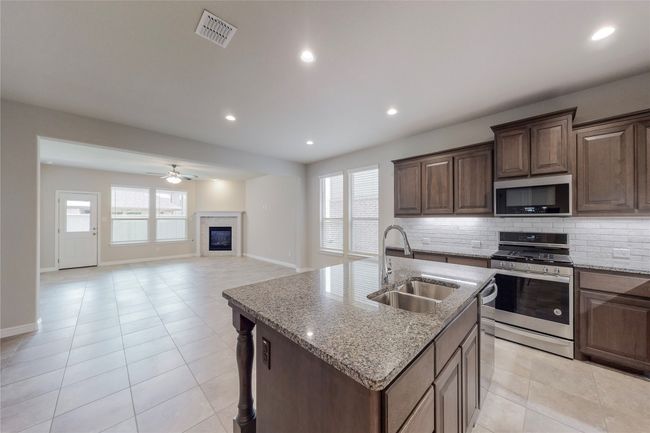Kitchen with stainless steel appliances, a sink, a ceiling fan, backsplash, and light tile patterned floors | Image 7