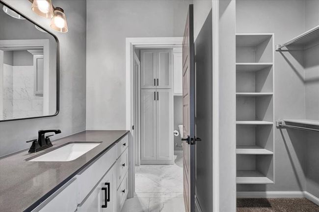 Full bath featuring vanity, a closet, and marble look tiles | Image 42