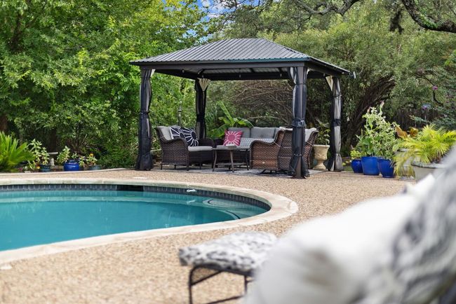 Gazebo nestled in the trees and landscaping near the koi pond. | Image 10