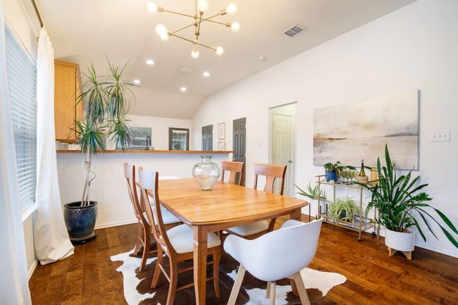 Dining room featuring lofted ceiling, wood finished floors, a chandelier, and recessed lighting | Image 7