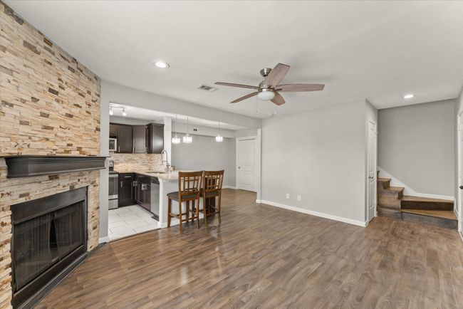 Living area with ceiling fan, stairway, wood finished floors, a stone fireplace, and recessed lighting | Image 9