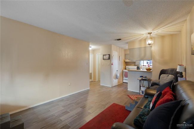 Living room with wood finished floors, a textured ceiling, and baseboards | Image 4