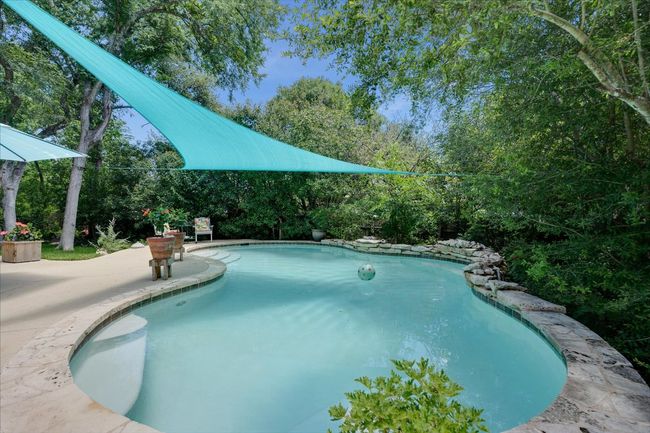 Outdoor pool featuring a waterfall and patio and view of lush greener | Image 7