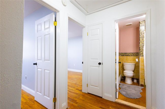 Hallway with attic access, wood finished floors, visible vents, and tile walls | Image 17