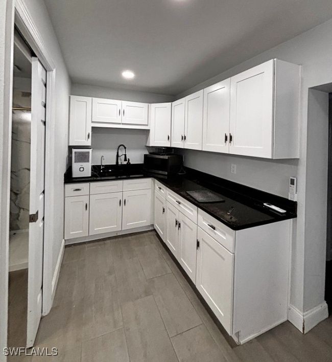 Kitchen featuring stainless steel microwave, white cabinets, and a sink | Image 7