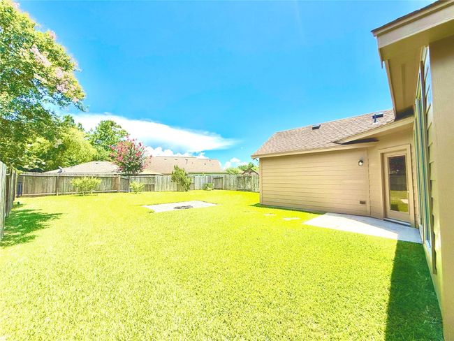 Spacious fenced backyard with a patio, ideal for outdoor gatherings. The area is well-maintained with lush grass and mature trees providing privacy. Property big enough to get a pool, play set area, or much more. | Image 23