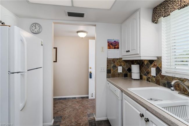 Kitchen with a sink, visible vents, backsplash, white cabinetry, and white appliances | Image 18