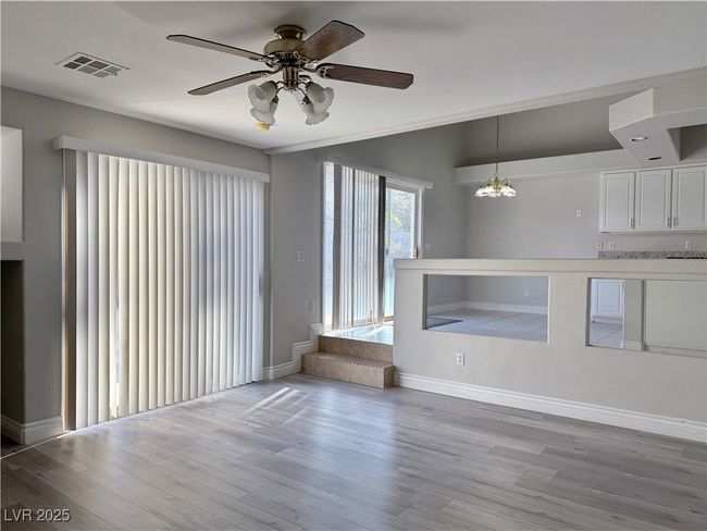 Unfurnished living room featuring visible vents, lofted ceiling, light wood-style floors, and ceiling fan with notable chandelier | Image 19