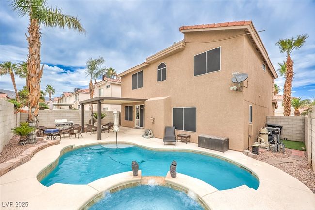 View of swimming pool with a patio area, a fenced backyard, and a pool with connected hot tub | Image 33