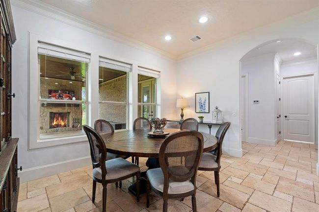 The Breakfast Room, located directly off the Kitchen, is illuminated by a trio of cased windows overlooking the Back Patio. There is plenty of space to accommodate just about any size table, as well as additional furniture like a buffet or drink cart. The archway straight ahead leads to the Powder Room, Laundry Room, and Game Room. | Image 21
