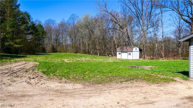 View of yard featuring an outdoor structure, a storage shed, and a wooded view | Image 37