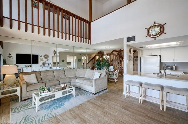 Living room featuring a high ceiling, sink, and light hardwood / wood-style tile floors | Image 6