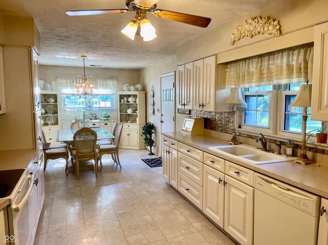 kitchen featuring white appliances, a ceiling fan, a textured ceiling, light countertops, and hanging light fixtures | Image 24