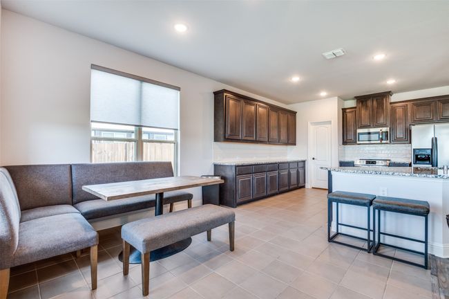 Kitchen featuring stainless steel appliances, dark brown cabinets, tasteful backsplash, recessed lighting, and light stone countertops | Image 11