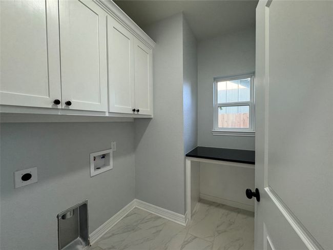 Laundry area with cabinet space, hookup for a washing machine, light marble finish flooring, and hookup for an electric dryer | Image 14