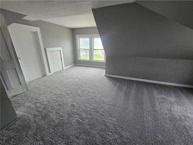 Additional living space featuring carpet flooring, baseboards, a textured ceiling, and vaulted ceiling | Image 13