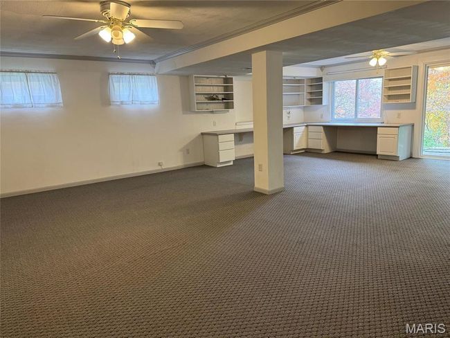Basement featuring ornamental molding, dark colored carpet, built in desk, and ceiling fan | Image 38