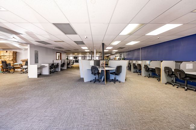 Misc room featuring carpet flooring, a drop ceiling, a desk, and electric panel | Image 4