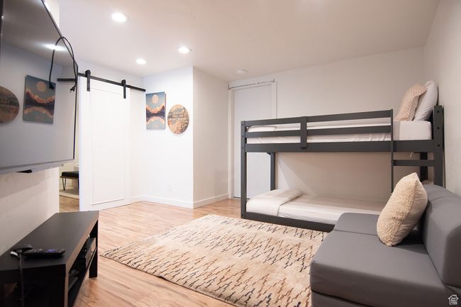 Bedroom with a barn door, light wood finished floors, recessed lighting, and baseboards | Image 29