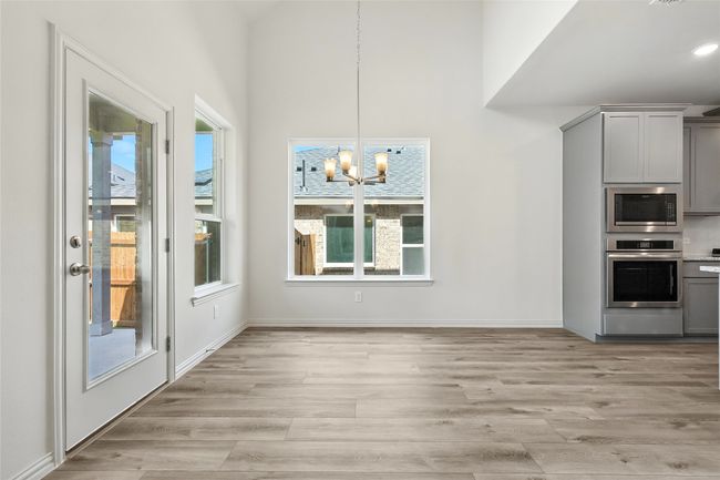 Unfurnished dining area featuring a chandelier and light wood-style flooring | Image 9