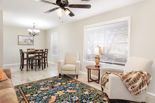 Living area with ceiling fan with notable chandelier, baseboards, and visible vents | Image 5
