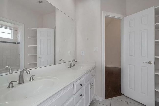 Bathroom with double vanity, tile patterned flooring, and a shower | Image 11
