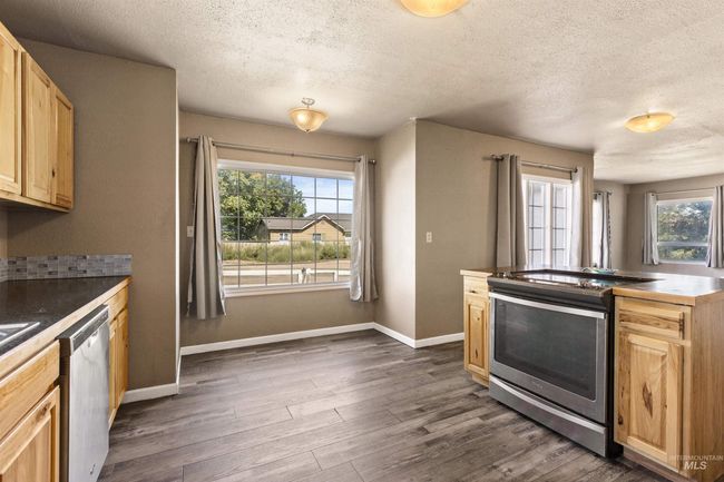 Kitchen featuring appliances with stainless steel finishes, light brown cabinetry, a textured ceiling, plenty of natural light, and dark wood-style flooring | Image 18