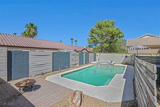 View of pool with a patio, a fenced backyard, a pool with connected hot tub, and an outdoor fire pit | Image 27