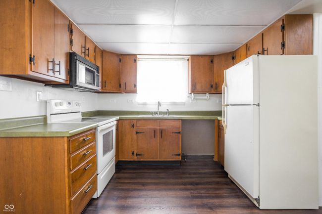 kitchen with white appliances, brown cabinets, and dark wood-style floors | Image 15
