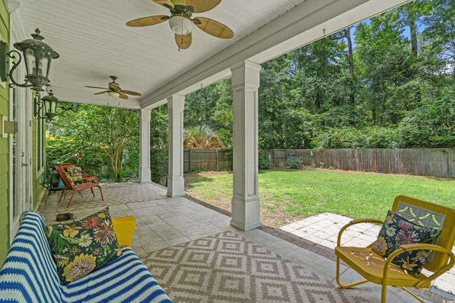 Fenced backyard with ceiling fan, a patio area, and view of wooded area | Image 20