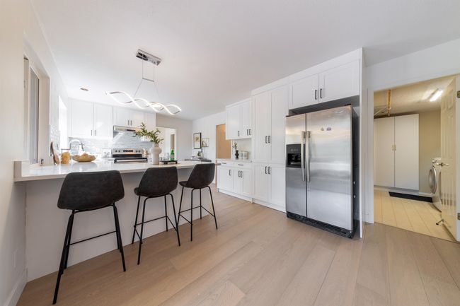 Kitchen with white cabinets, light wood-style floors, a peninsula, and appliances with stainless steel finishes | Image 15
