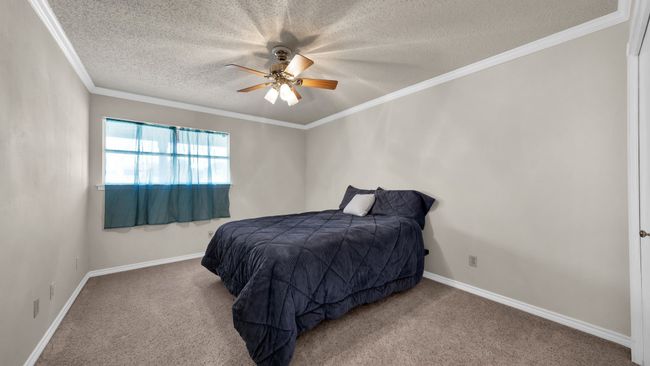 Bedroom with ceiling fan, carpet, crown molding, and a textured ceiling | Image 20
