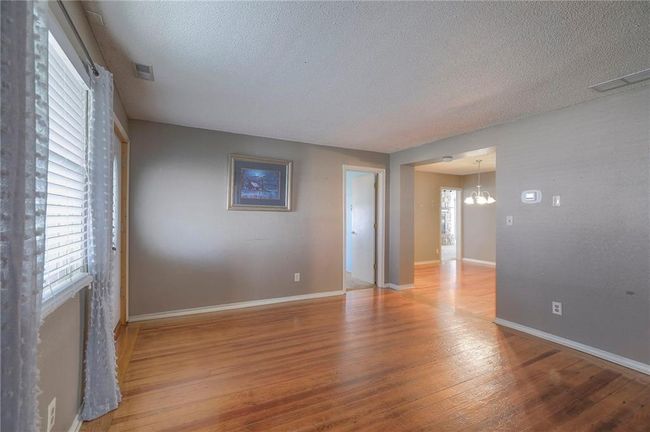 Unfurnished room featuring a notable chandelier, a textured ceiling, baseboards, visible vents, and hardwood / wood-style floors | Image 37