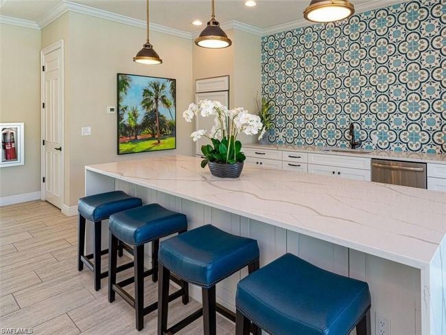 Kitchen featuring light stone countertops, stainless steel dishwasher, hanging light fixtures, white cabinetry, and a breakfast bar area | Image 25