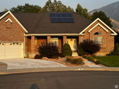 Single story home featuring solar panels, a front yard, and a garage | Image 1