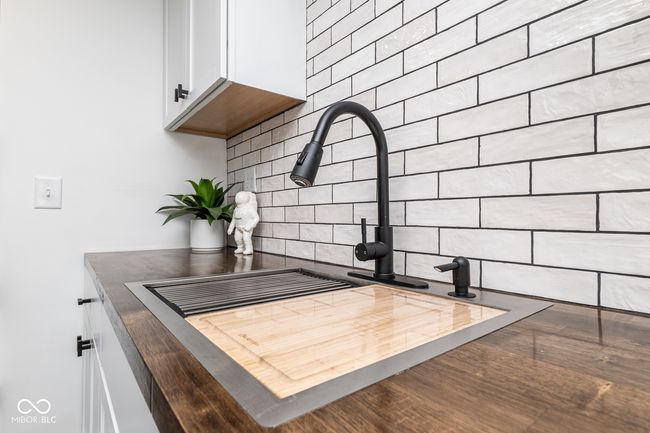 interior details with white cabinets, a sink, tasteful backsplash, dark countertops, and a wood stove | Image 11