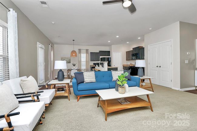 Living room view showing open flow to kitchen & dining area, as well as downstairs storage closet. | Image 6