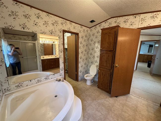 Full bathroom featuring vaulted ceiling, crown molding, wallpapered walls, a stall shower, and a garden tub | Image 22