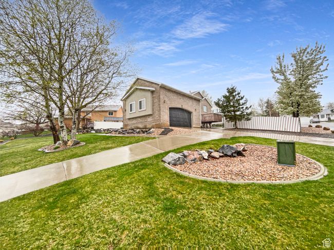 View of front of home with a front lawn, driveway, an attached garage, fence, and stucco siding | Image 20
