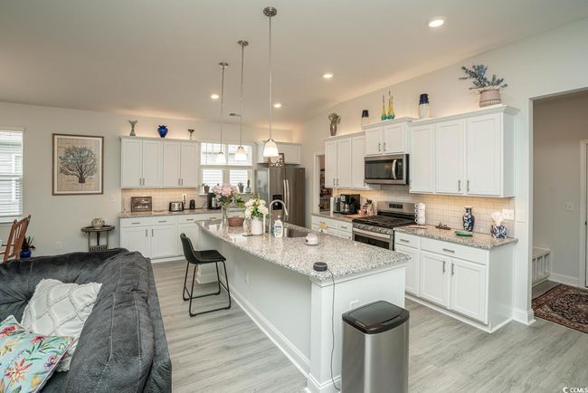 Kitchen with appliances with stainless steel finishes, light wood-style floors, backsplash, a breakfast bar, and recessed lighting | Image 17