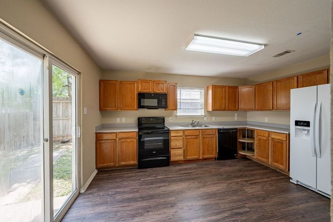 Kitchen with black appliances, a sink, light countertops, and healthy amount of natural light | Image 9