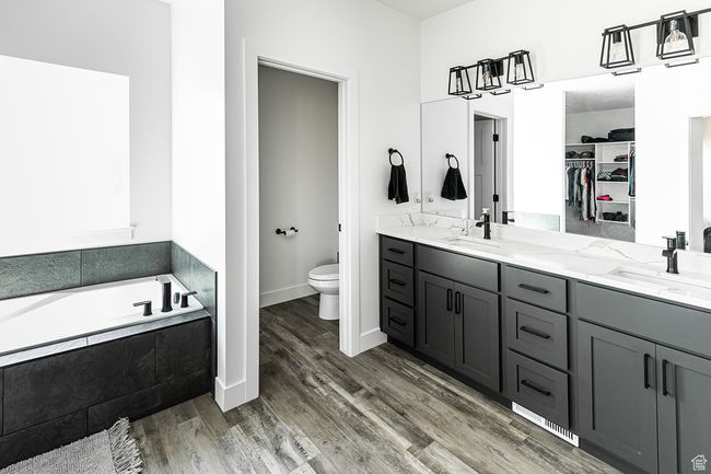 Bathroom with wood finished floors, toilet, double vanity, and a sink | Image 11