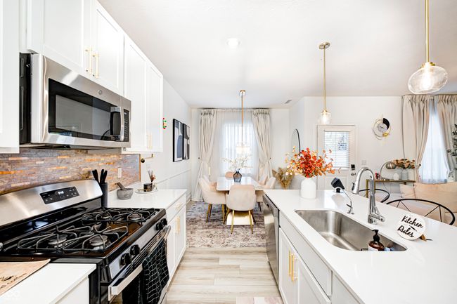 kitchen featuring white cabinets, stainless steel appliances, light countertops, and a sink | Image 11