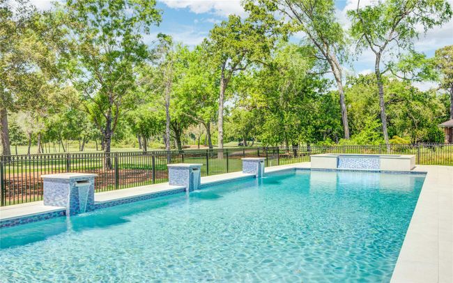 This stunning pool, framed by golf course vistas, boasts multiple waterfall features for a soothing and refined outdoor experience. | Image 29