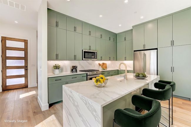 Kitchen featuring green cabinets, appliances with stainless steel finishes, recessed lighting, a breakfast bar area, and light wood finished floors | Image 6