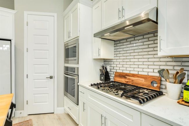 The kitchen features white cabinets, creating a clean and timelessaesthetic. | Image 20