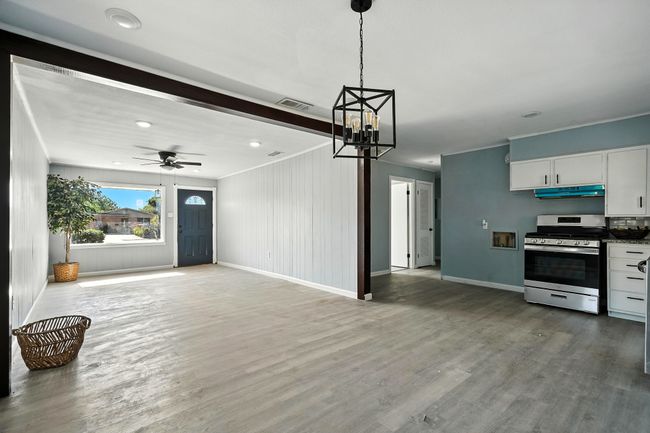 Unfurnished living room with a chandelier, wood finished floors, a ceiling fan, and recessed lighting | Image 4