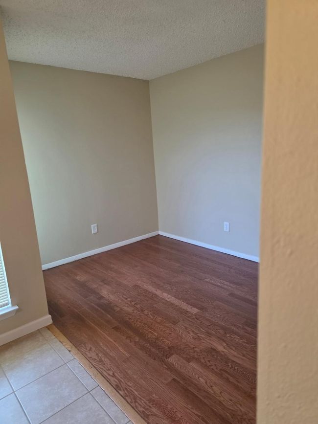 Empty room with a textured ceiling and light wood-style floors | Image 13