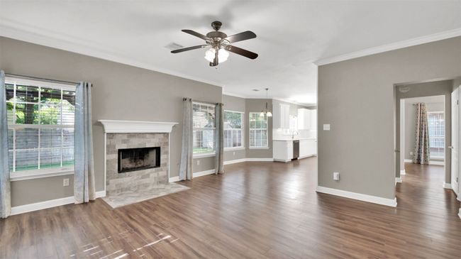 Different view of living room- molding, baseboards, good amount of natural light, a tiled fireplace, and ceiling fan | Image 10