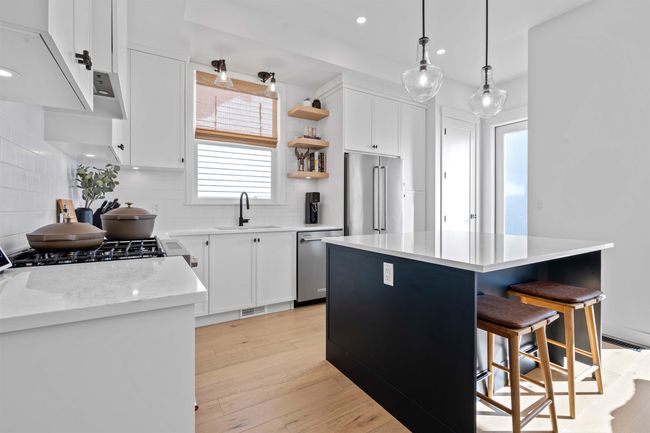 Kitchen with tasteful backsplash, a kitchen island, light wood-style flooring, appliances with stainless steel finishes, and a sink | Image 10